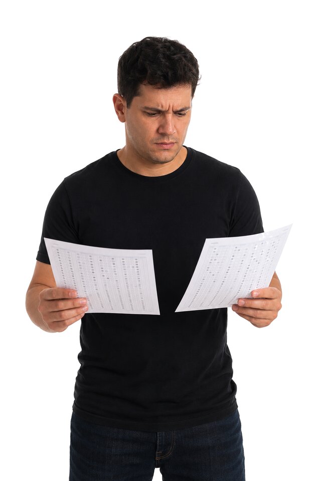 Candidato de camiseta preta conferindo o gabarito, com expressão preocupada.
